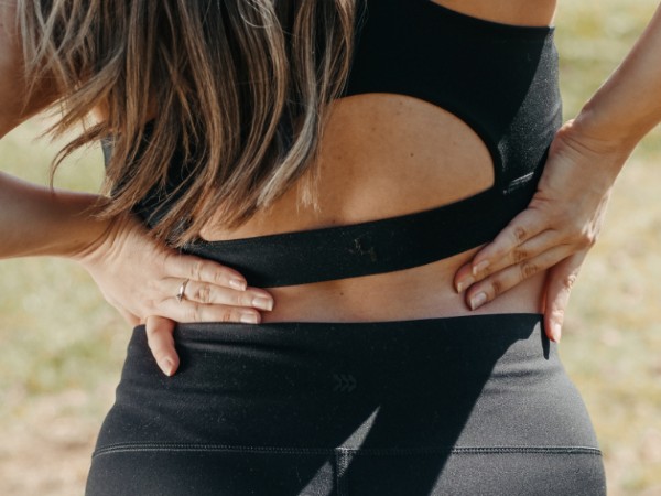 a person rubbing their lower back due to pain.