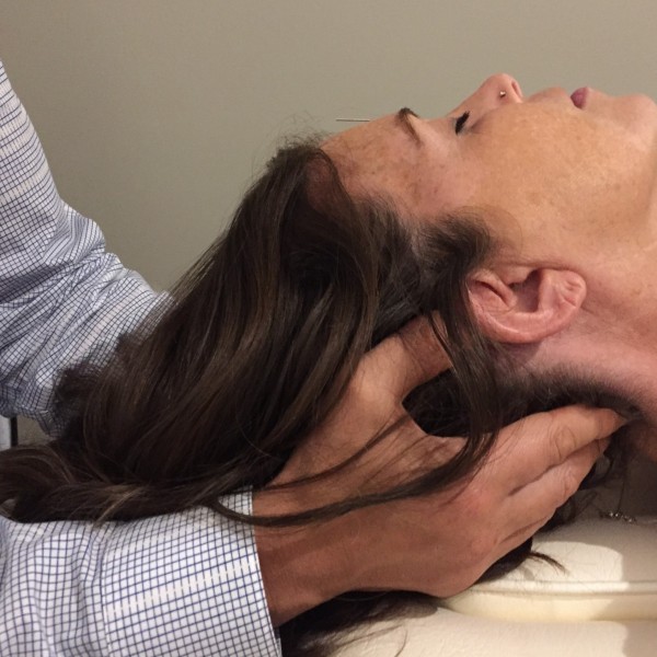 a patient receiving a craniosacral head massage treatment in the Oakville office.